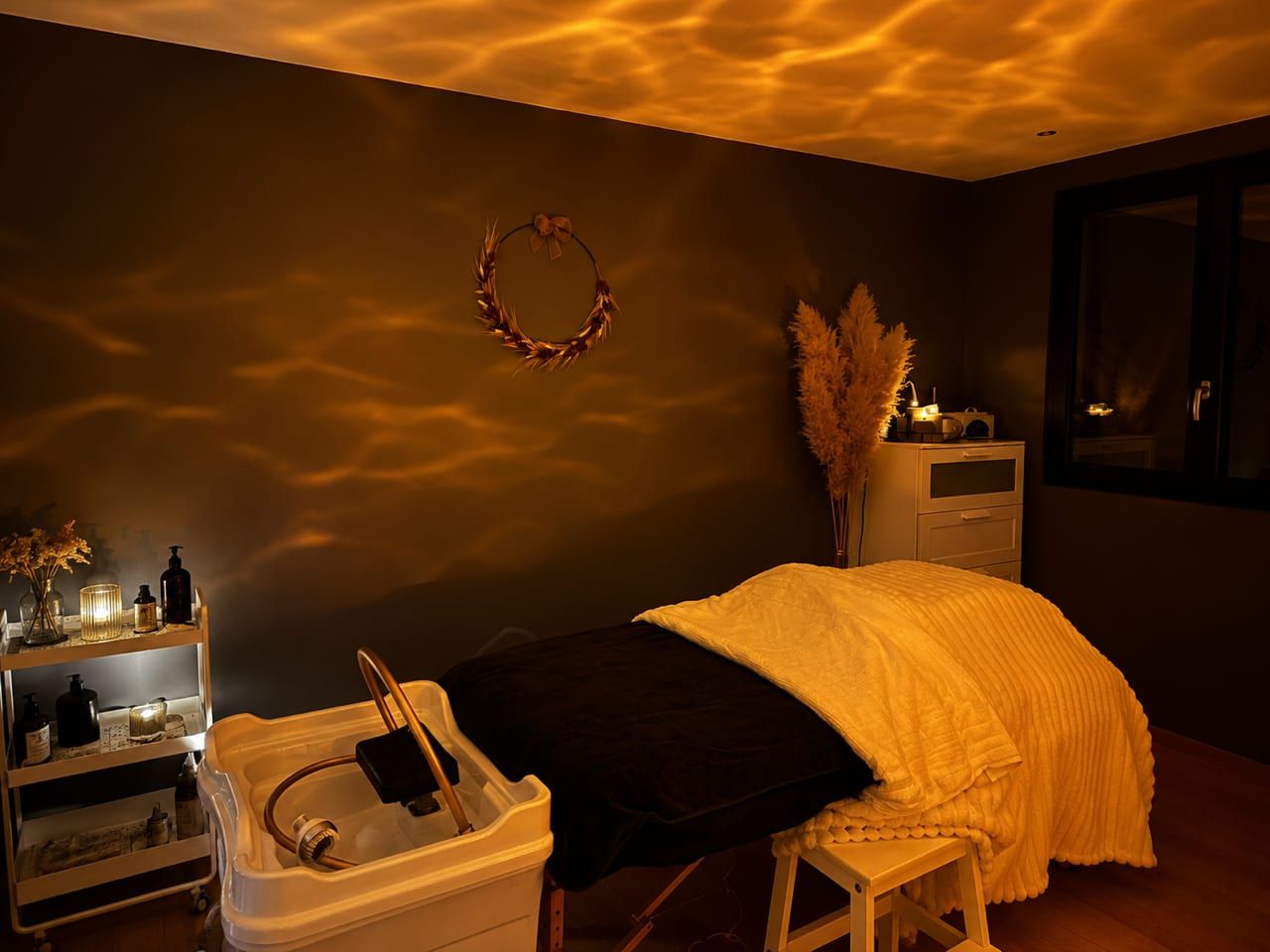 Cabine head spa Maison Clélia à Thionville : table de soin, plaid crème, bac de lavage et lumière tamisée